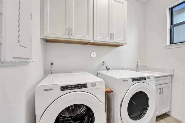 laundry area featuring sink, cabinets, independent washer and dryer, and light hardwood / wood-style flooring