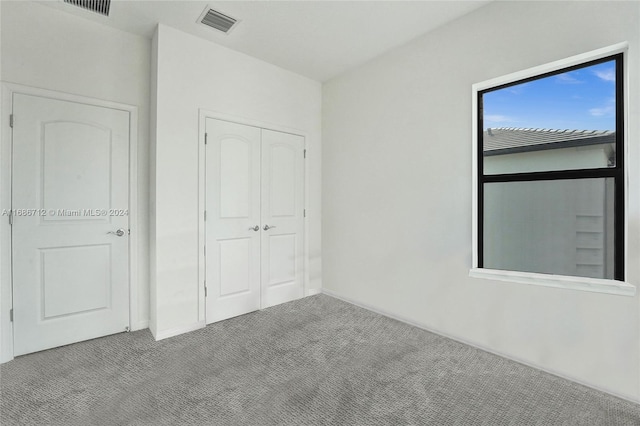 unfurnished bedroom with light carpet and a closet