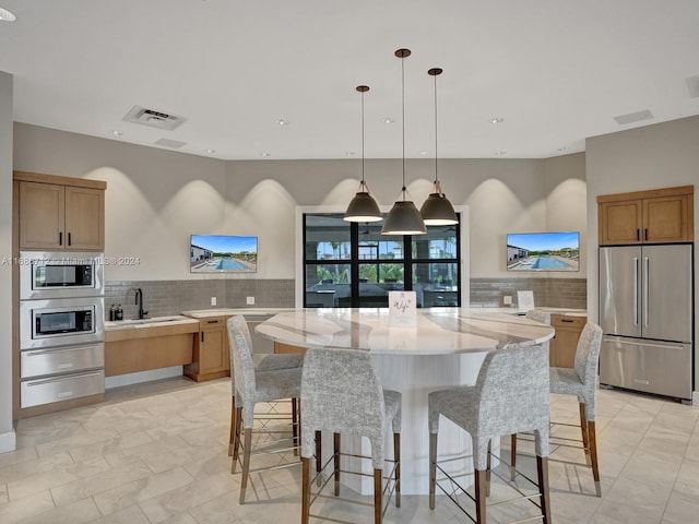 kitchen featuring a large island, appliances with stainless steel finishes, decorative light fixtures, and light stone countertops