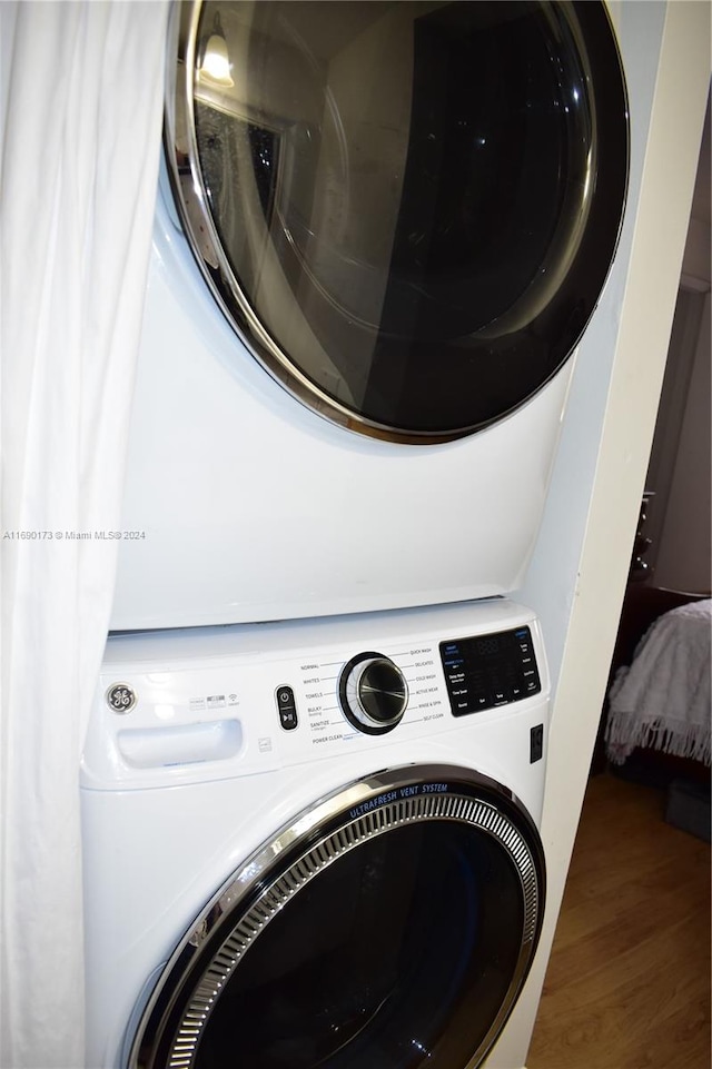 laundry area featuring wood-type flooring and stacked washer and clothes dryer