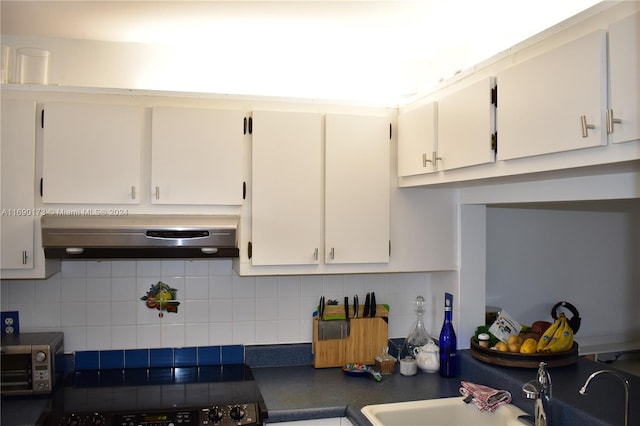 kitchen featuring exhaust hood, white cabinets, black range oven, sink, and decorative backsplash