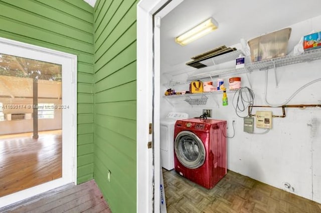 laundry area with washing machine and dryer, wooden walls, and dark parquet floors