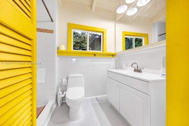 bathroom featuring toilet, vanity, tile walls, and a tile shower