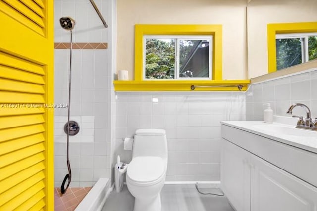 bathroom featuring tile walls, a tile shower, vanity, and toilet