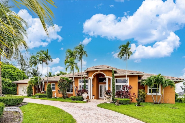 mediterranean / spanish home featuring a front yard and a garage