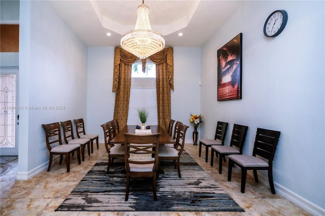 dining space with a notable chandelier and a raised ceiling