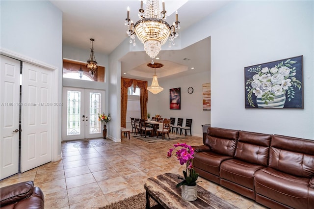 living room featuring a towering ceiling, an inviting chandelier, and french doors