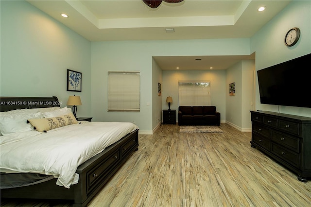 bedroom featuring a raised ceiling and light hardwood / wood-style flooring