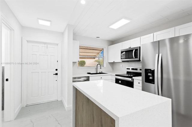 kitchen featuring white cabinets, appliances with stainless steel finishes, sink, and a center island