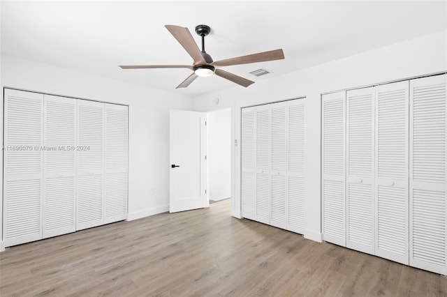 unfurnished bedroom featuring ceiling fan, multiple closets, and light hardwood / wood-style flooring