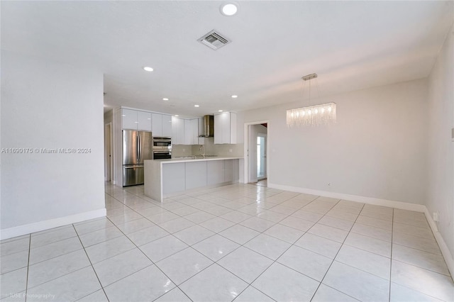 kitchen with pendant lighting, kitchen peninsula, wall chimney exhaust hood, white cabinetry, and appliances with stainless steel finishes