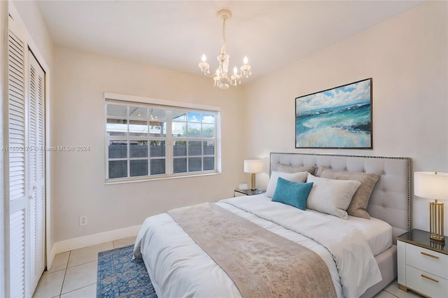 bedroom with light tile patterned floors, an inviting chandelier, and a closet