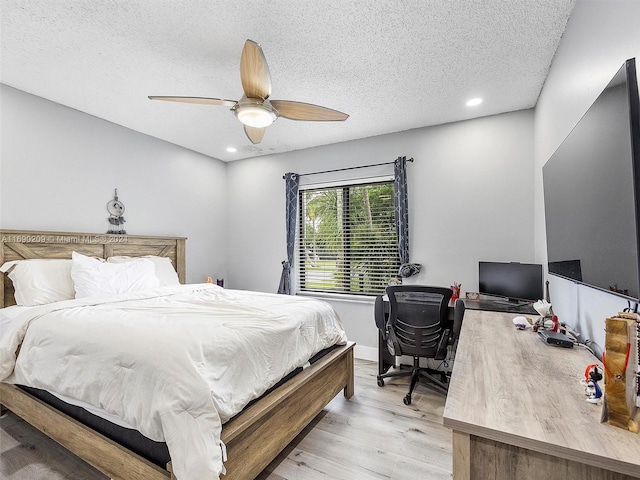 bedroom with light hardwood / wood-style floors, ceiling fan, and a textured ceiling