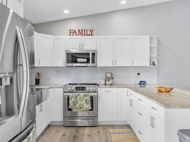 kitchen with light hardwood / wood-style floors, light stone counters, vaulted ceiling, white cabinets, and appliances with stainless steel finishes