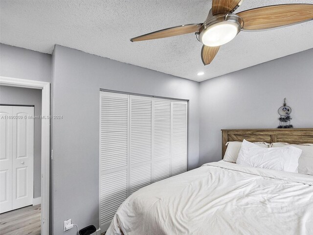 bedroom with a textured ceiling, light hardwood / wood-style flooring, and ceiling fan