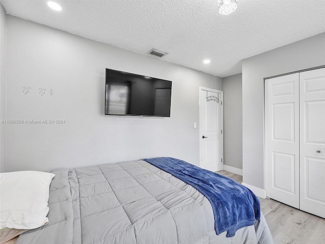 bedroom with light wood-type flooring and a textured ceiling