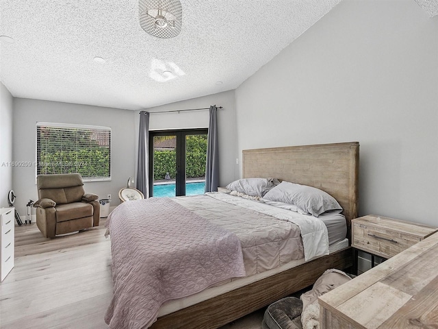 bedroom featuring access to outside, lofted ceiling, a textured ceiling, and light hardwood / wood-style floors