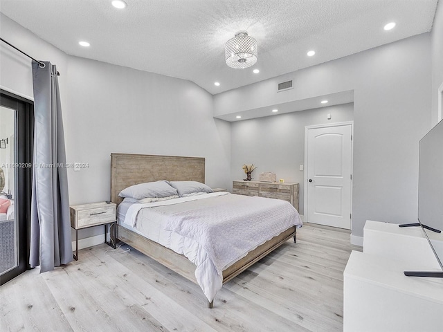 bedroom with an inviting chandelier, a textured ceiling, and light hardwood / wood-style floors