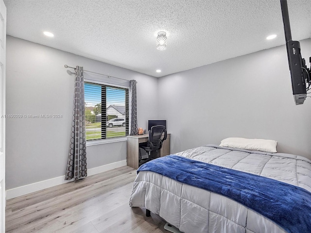 bedroom with a textured ceiling and light wood-type flooring