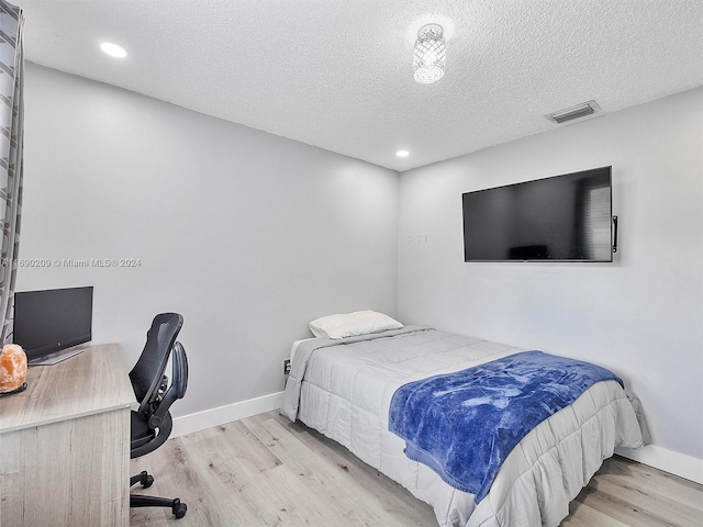 bedroom featuring a textured ceiling and light hardwood / wood-style floors