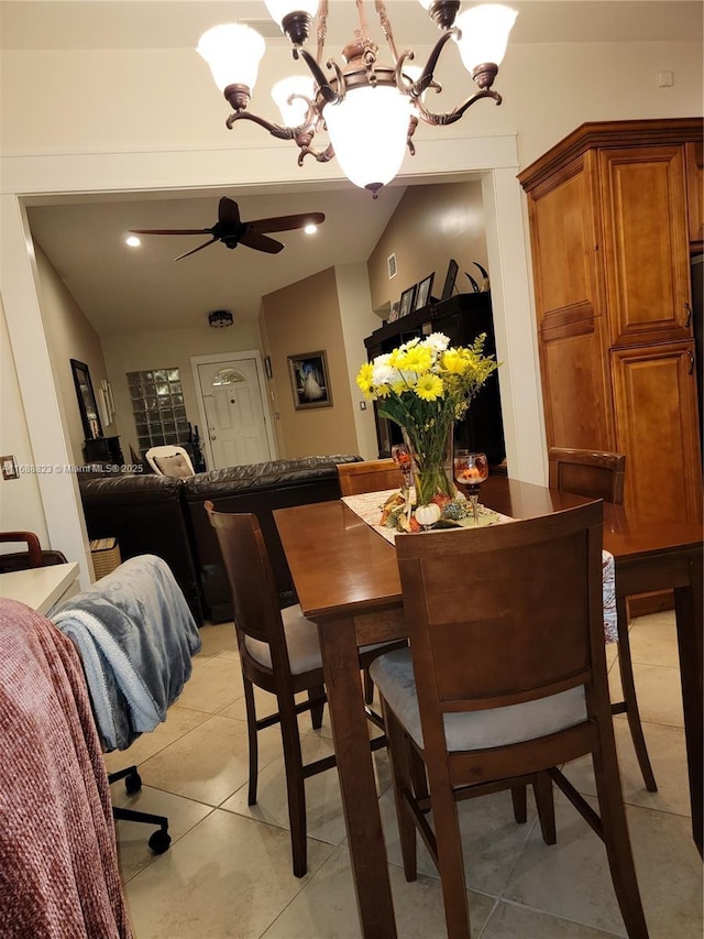 dining area with lofted ceiling, light tile patterned floors, and ceiling fan with notable chandelier