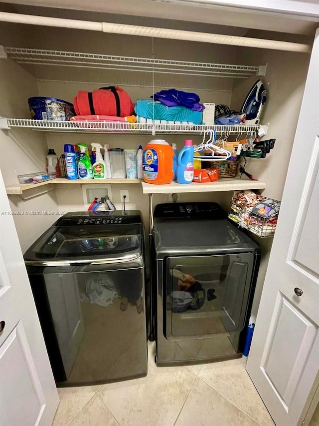 clothes washing area featuring light tile patterned flooring and separate washer and dryer