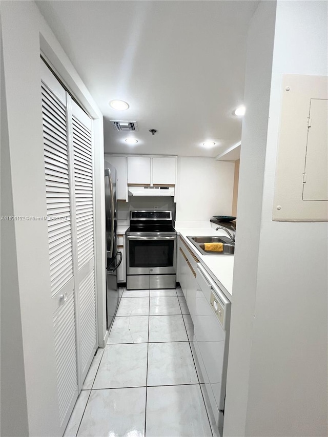 kitchen with appliances with stainless steel finishes, sink, light tile patterned floors, electric panel, and white cabinetry