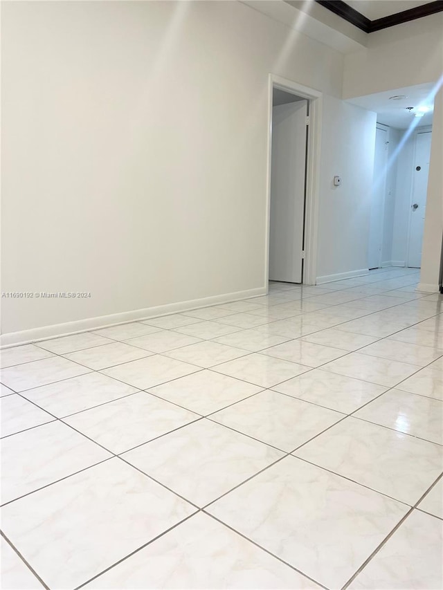 unfurnished room featuring light tile patterned floors and crown molding