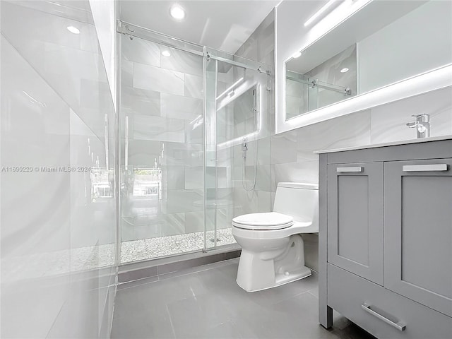 bathroom with tile walls, tile patterned floors, vanity, an enclosed shower, and toilet