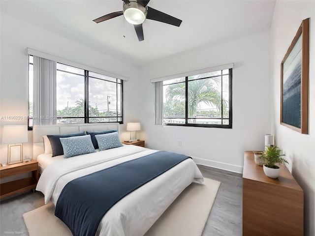 bedroom featuring dark wood-type flooring, ceiling fan, and multiple windows