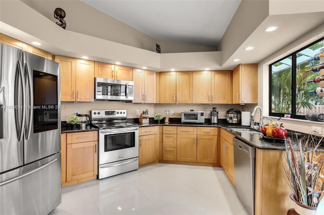 kitchen with dark stone countertops, sink, light tile patterned flooring, and stainless steel appliances