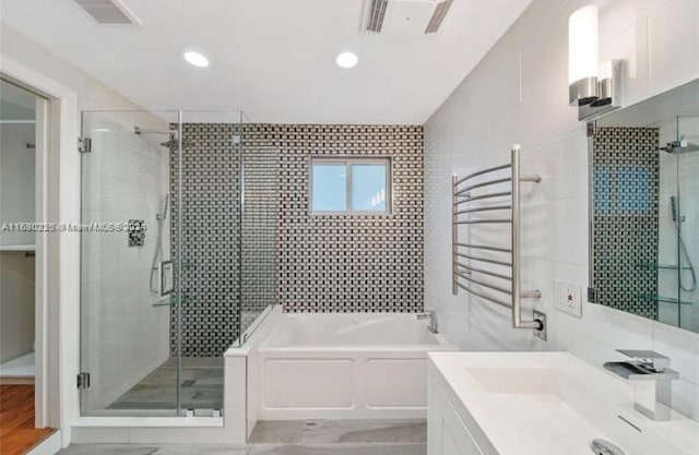 bathroom featuring radiator heating unit, shower with separate bathtub, and tile walls