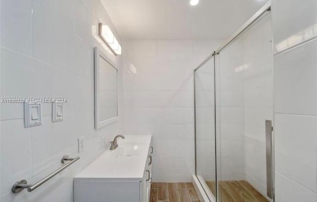 bathroom with walk in shower, vanity, and tile walls