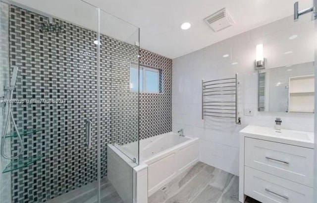 bathroom with tile walls, shower with separate bathtub, and vanity