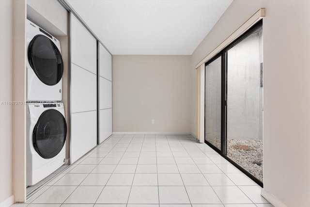 clothes washing area with light tile patterned floors and stacked washing maching and dryer