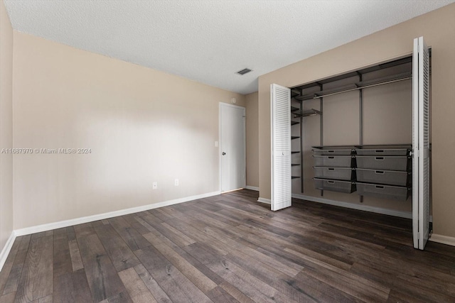 unfurnished bedroom featuring a textured ceiling, a closet, and dark hardwood / wood-style floors