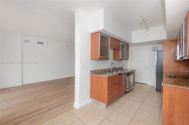 kitchen featuring stainless steel appliances, stone counters, sink, rail lighting, and light hardwood / wood-style flooring