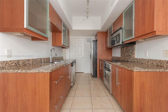 kitchen featuring stone counters, sink, light tile patterned flooring, and stainless steel appliances