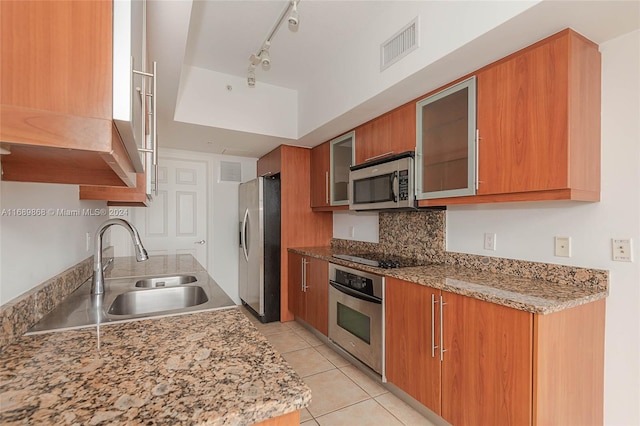 kitchen with light stone countertops, appliances with stainless steel finishes, sink, and light tile patterned floors