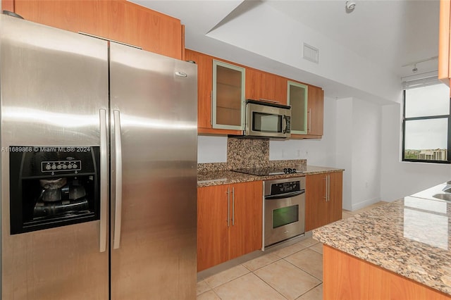 kitchen with stainless steel appliances, light tile patterned floors, tasteful backsplash, stone counters, and rail lighting