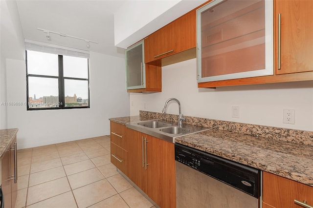 kitchen featuring sink, dark stone countertops, rail lighting, light tile patterned floors, and dishwasher