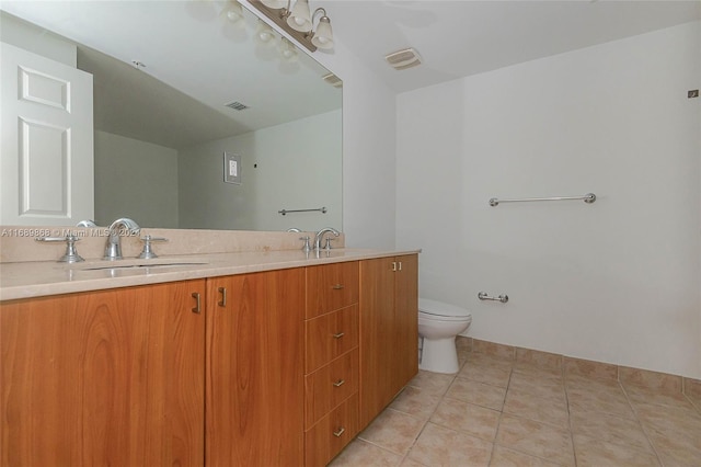 bathroom with toilet, vanity, and tile patterned flooring