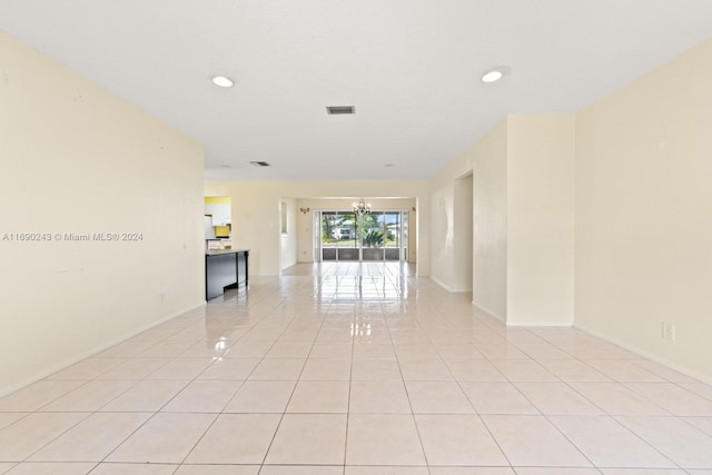 empty room with a chandelier and light tile patterned floors