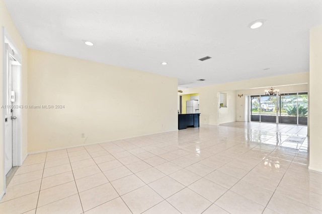 tiled empty room featuring an inviting chandelier