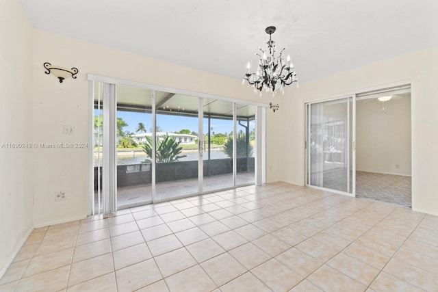 unfurnished room with a chandelier, a water view, and light tile patterned floors