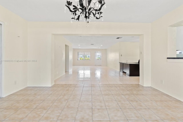 tiled empty room featuring a chandelier