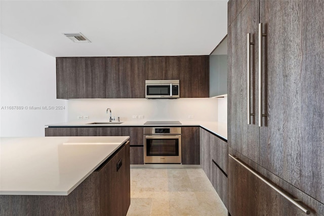 kitchen with dark brown cabinets, appliances with stainless steel finishes, and sink