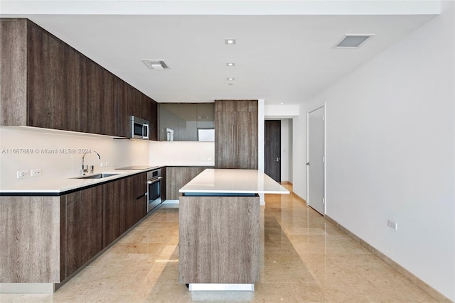 kitchen featuring dark brown cabinets, stainless steel appliances, sink, and a kitchen island