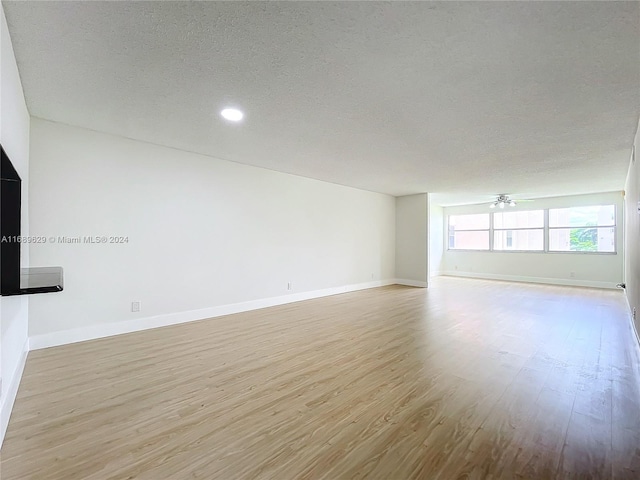 unfurnished room with ceiling fan, light hardwood / wood-style floors, and a textured ceiling