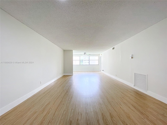 spare room featuring ceiling fan, light hardwood / wood-style floors, and a textured ceiling